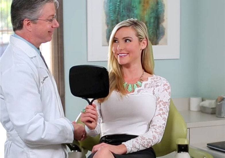 Dr. Gross consulting with a female patient looking in the mirror