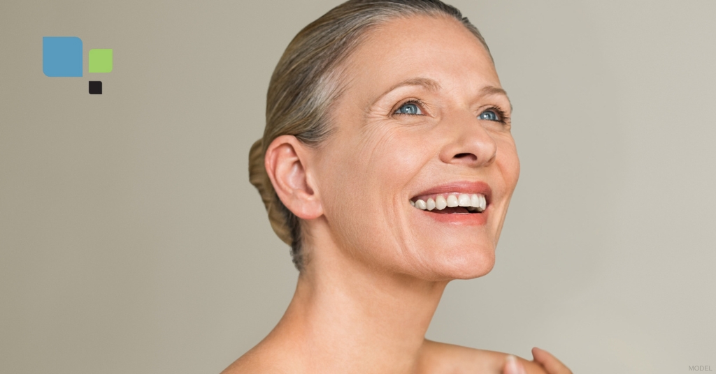 Mature woman smiling looking up at the camera (model) Primera Plastic Surgery Logo