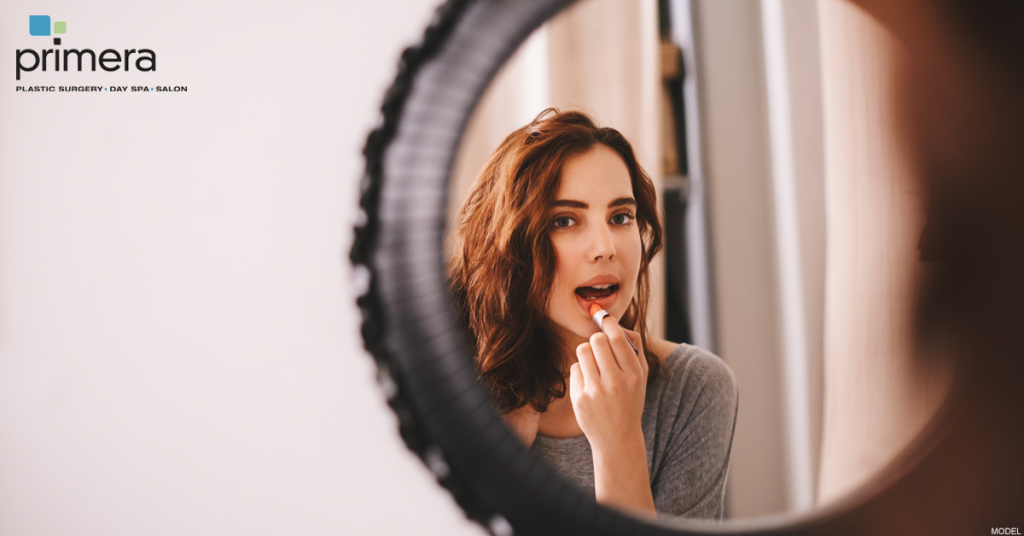 Woman applying lipstick after lip injections