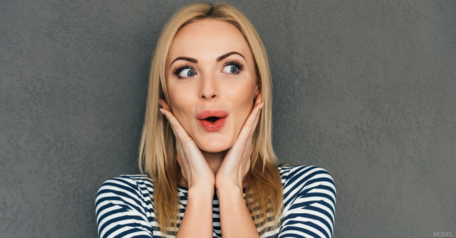 Woman with red lipstick looking surprised with hands cupping her cheeks