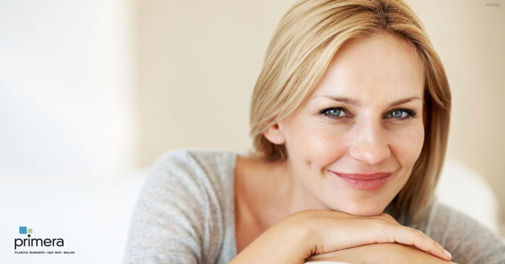 Naturally attractive blonde woman smiling and resting her chin on hands