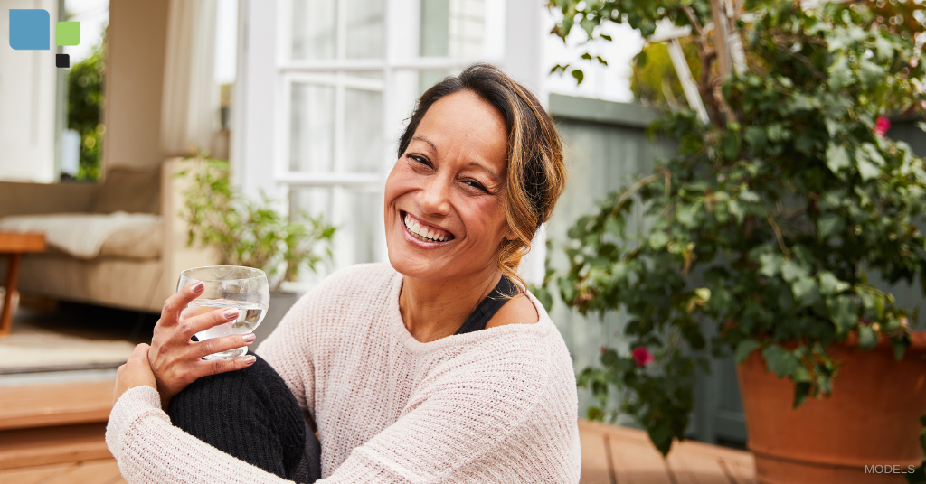 Woman smiling and holding a glass of water on her patio in Orlando, FL