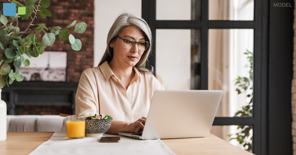 A mature woman researching facelift surgeons on a computer in her home near Orlando, FL