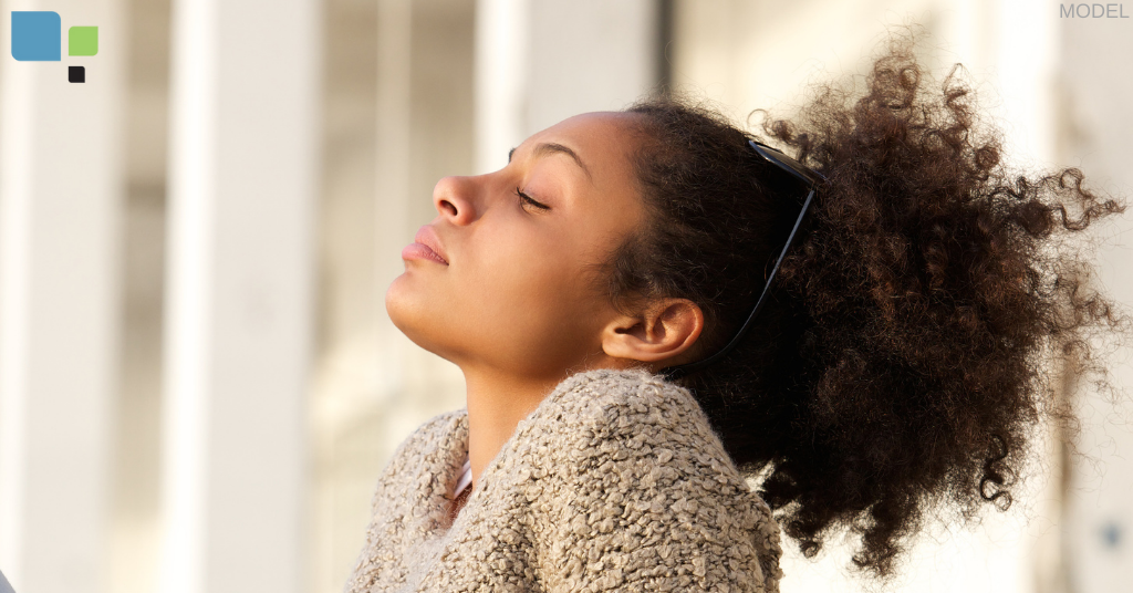 A close up of a woman with eyes closed looking at the sun (model)