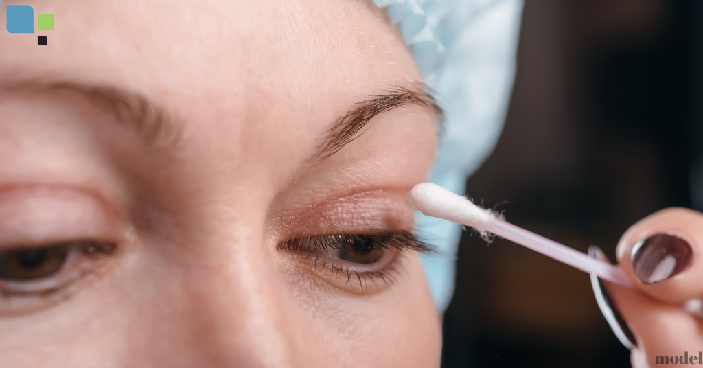 woman holding a q tip to her upper eyelid (model)