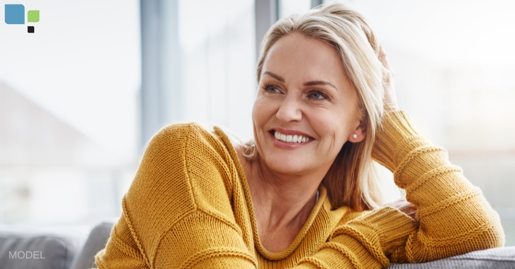 middle-aged woman with beautiful skin resting on a couch smiling (model)