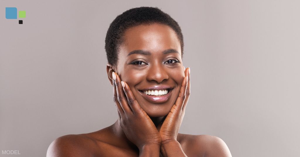 A woman holding her face and smiling (model)