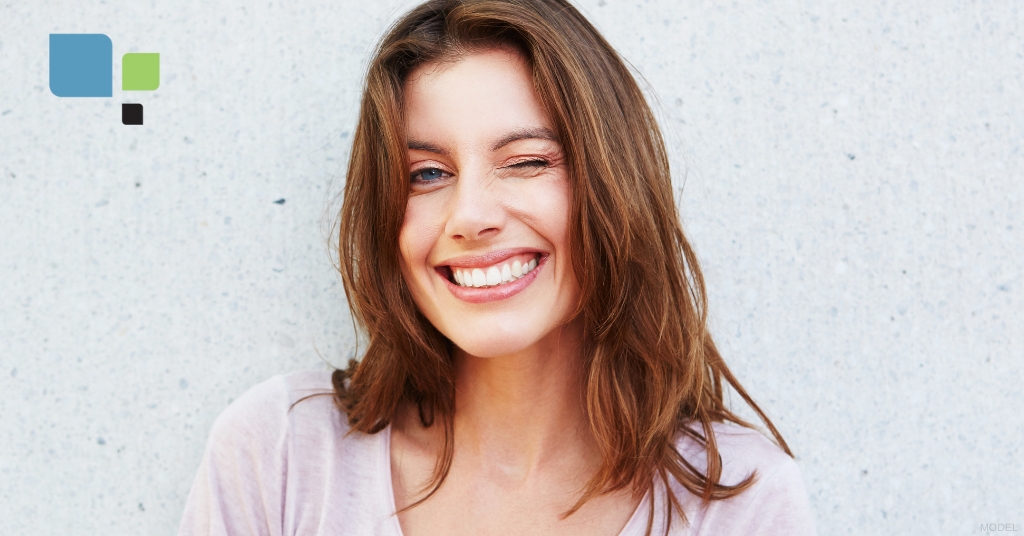 young woman is smiling while standing in front of a wall (model)