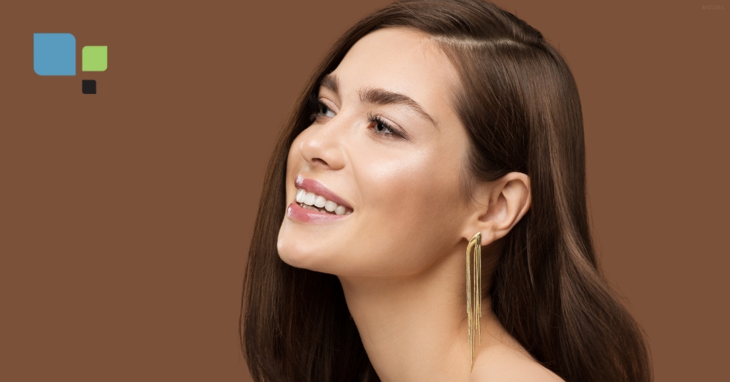 Young woman with long brown hair smiling and looking up (model) Primera Plastic Surgery Logo